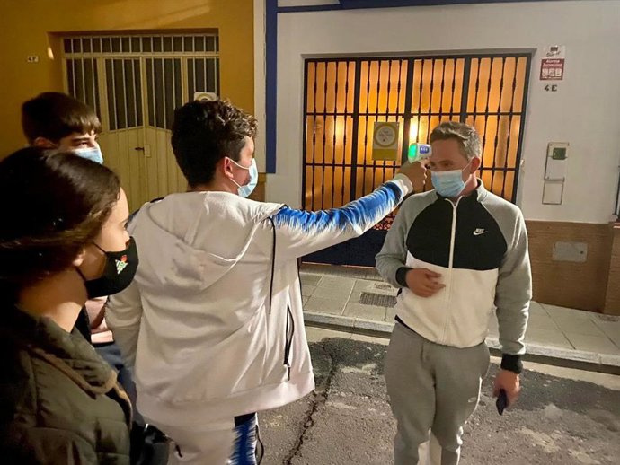 Jóvenes del equipo 'anticovid' de Rociana del Condado (Huelva) toman la temperatura a uno de sus vecinos.