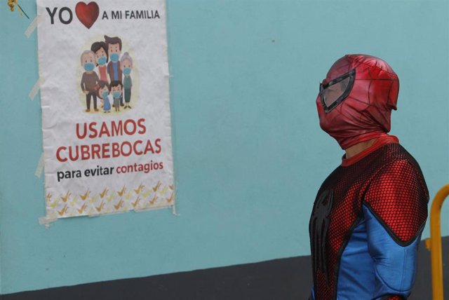 Hombre junto a un cartel de concienciación por el coronavirus en México