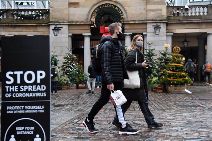 18 December 2020, England, London: People walk past a sign advising social distancing in Covent Garden. Photo: Kirsty O'connor/PA Wire/dpa