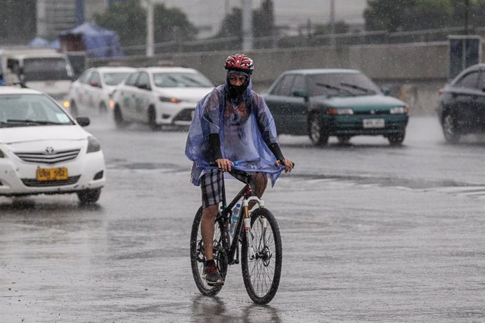 Un home circula amb bicicleta per Manila sota la pluja