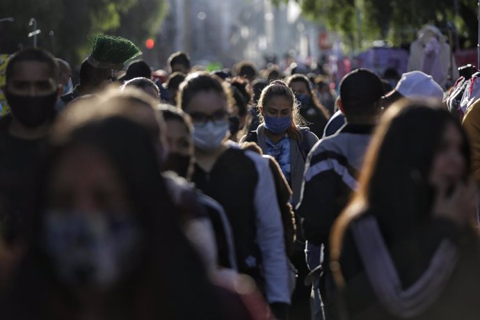 16 December 2020, Colombia, Bogota: Numerous people walk through the San Victorino square, where discounts are offered this morning before Christmas. The city government decided that they will put workers on the streets to spray disinfectant on people d