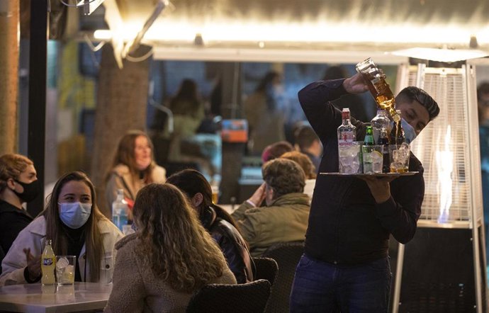 Un camarero sirve alcohol después de las 20h en la terraza de un bar tras la apertura de bares y restaurantes de 20 a 22,30 horas con la flexibilización de restricciones de la Junta de Andalucía. En Sevilla (Andalucía, España), a 18 de diciembre de 2020.
