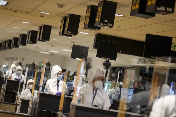 HANDOUT - 05 October 2020, Peru, Lima: Airport employees in protective suits operate at the passport control desks of the Jorge Chavez airport after international flights resumed following a long shutdown due to the coronavirus pandemic. Photo: Andres V