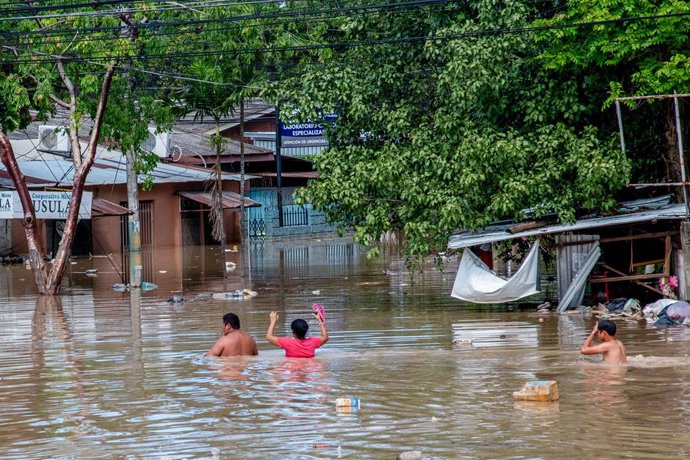19 November 2020, Honduras, La Lima: A family wades through shoulder high floodwaters after the devastating hurricane Iota made landfall in Honduras. Photo: Seth Sidney Berry/SOPA Images via ZUMA Wire/dpa