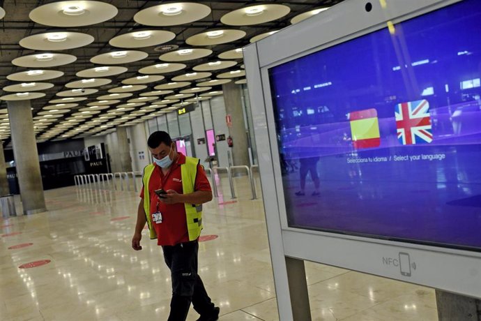 Un operario de Iberia pasa al lado de un monitor con las banderas de España y Reino Unido en la T1 del Aeropuerto de Madrid-Barajas Adolfo Suárez, en Madrid (España), a 27 de julio de 2020. 