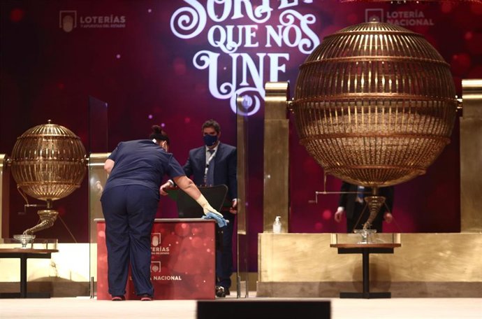 Una empleada limpia la mesa del Sorteo para que se cumplan todas las medidas de higiene durante la celebración del Sorteo Extraordinario de la Lotería de Navidad 2020 en el Teatro Real de Madrid (España), a 22 de diciembre de 2020.