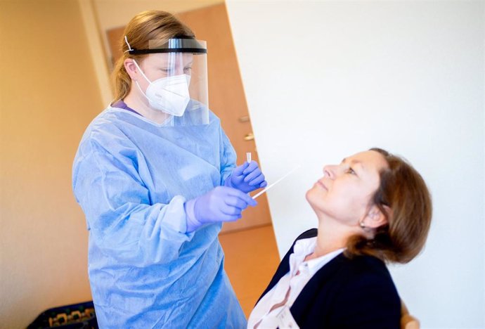 21 December 2020, Lower Saxony, Oldenburg: Carina Glinsmann, deputy nursing service manager at the AWO's "Haus am Floetenteich" retirement home, takes a swab from a woman for a coronavirus test. Rapid tests are intended to enable visits by relatives dur