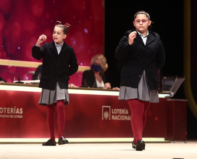 Dos de las niñas de la residencia de San Ildefonso, Judith García Benítez (i) y  Nerea Pareja Martínez (d) cantan un premio de la Lotería de Navidad, el `52.472, durante la celebración del Sorteo Extraordinario de la Lotería de Navidad 2020.