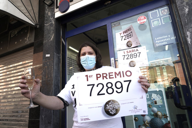 Una lotera posa con `El Gordo´ y celebra con champán en la administración de lotería situada en la calle Zurbarambarri, 1 en la que se ha repartido parte del número '72897´ correspondiente a 'El Gordo' de la Lotería de Navidad, en Bilbao