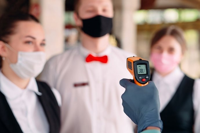 Imagen de archivo de una toma de temperatura a empleados de un hotel.