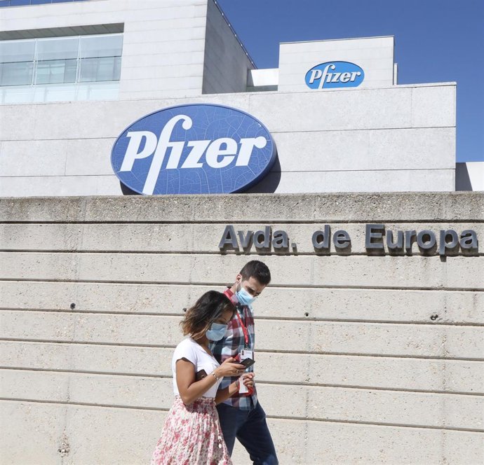Una pareja pasa junto al edificio de los laboratorios Pfizer, en Madrid (España), a 2020.  