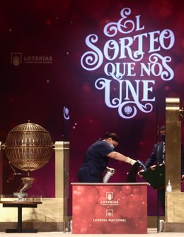 Una empleada limpia la mesa del Sorteo para que se cumplan todas las medidas de higiene durante la celebración del Sorteo Extraordinario de la Lotería de Navidad 2020 en el Teatro Real de Madrid (España), a 22 de diciembre de 2020.