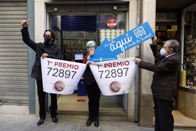 Loteros posan en la administración de lotería situada en la calle Principe 11 , en la que se ha repartido parte del número '72897 correspondiente  a 'El Gordo' de la Lotería de Navidad, en Granada   (Andalucía, España), a 22 de diciembre de 2020