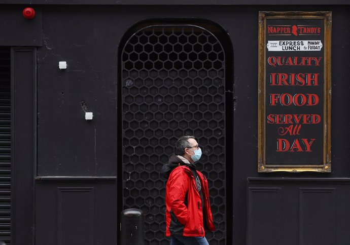 18 December 2020, Ireland, Dublin: A man passes by a closed pub in Dublin's city centre as restrictions have been eased in the lead up to the Christmas period. Photo: Brian Lawless/PA Wire/dpa