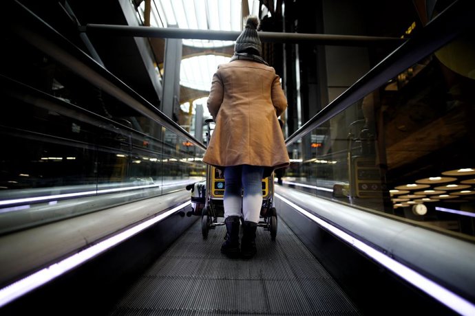Una mujer sube las escaleras mecánicas en la terminal T4 del Aeropuerto Adolfo Suárez Madrid-Barajas.