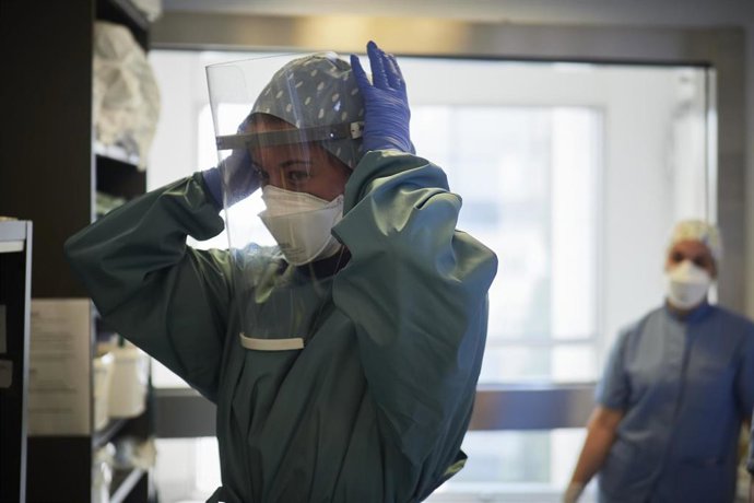 Una trabajadora sanitaria se coloca una pantalla protectora antes de entrar a una habitación de la UCI de la Clínica Universidad de Navarra, en Pamplona, Navarra, (España)