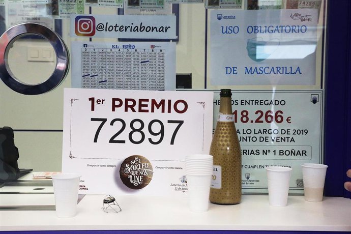 El premio `Gordo de la Lotería de Navidad junto a una botella de champán en la administración de lotería situada en la avenida de la Constitución, 52 en la que se ha repartido parte del número '72897 correspondiente a 'El Gordo' de la Lotería de Navidad