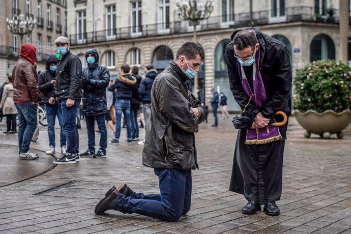 FILED - 15 November 2020, France, Nantes: A Catholic priest listens to the confession of a believer during a gathering to call the reopening of places of worship as the national lockdown in France counties to stop the spread of the coronavirus. Photo: S