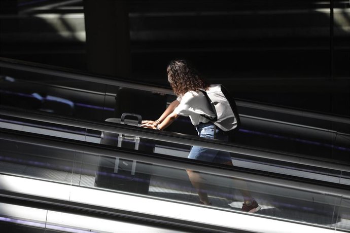 Una pasajera con maleta en una terminal de aeropuerto.
