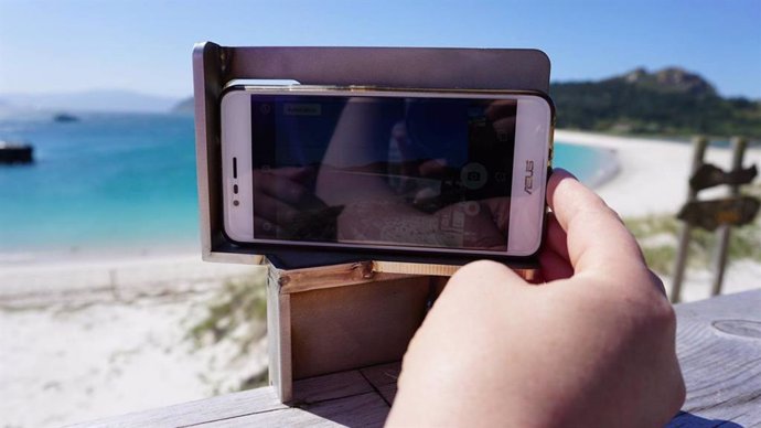 Un visitante toma una fotografía con su teléfono móvil en la playa
