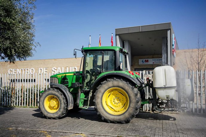 Un agricultor montado en su tractor desinfecta las inmediaciones del Centro de Salud de Aranjuez, dentro del protocolo de actuación activado por la Comunidad de Madrid en el que agricultores de la región colaboran con sus tractores.  