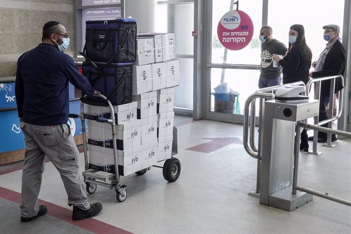 Un operario lleva en un carro varias cajas con vacunas de Pfizer.
