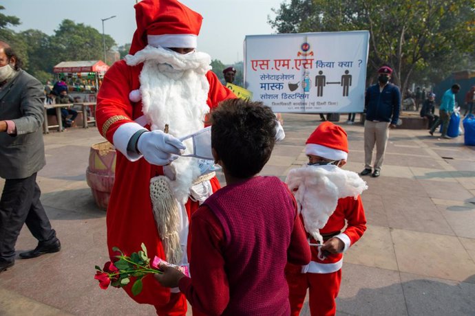 Un hombre disfrazado de Papá Noel reparte mascarillas en Nueva Delhi