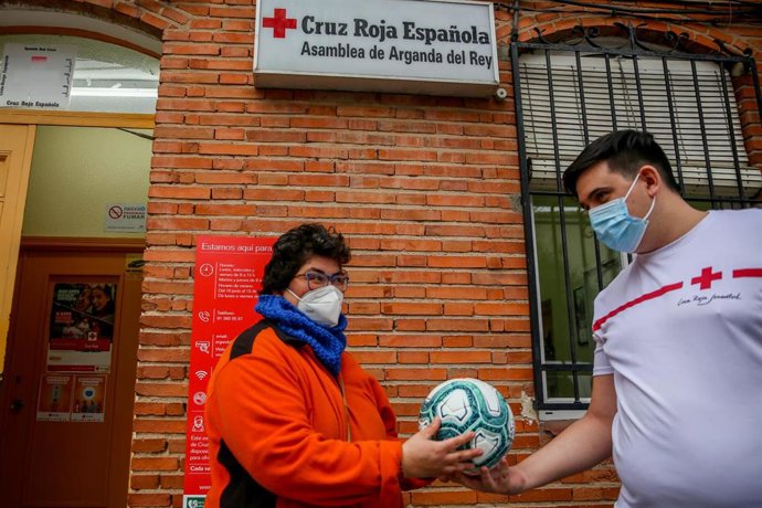Una voluntaria de Cruz Roja en la Asamblea de Arganda del Rey de Cruz Roja Española realiza un reparto de juguetes a una vecina 