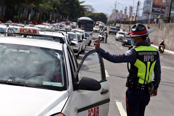 17 March 2020, Philippines, Manila: A policeman talks to a driver near a checkpoint in Manila. President Duterte has placed the whole of Luzon - the largest island in the Philippines with 57 million people - under "tightened quarantine" and tightened th