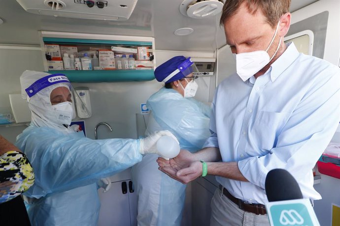 09 October 2020, Chile, Vina Del Mar: A health care worker helps officer Arturo Zuniga (R) disinfect his hands at a Covid-19 testing station. Photo: Leonardo Rubilar/Agencia Uno/dpa