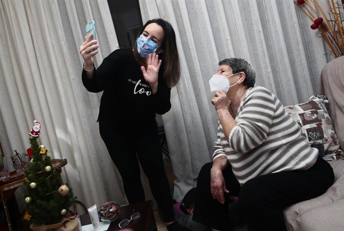 Una mujer viuda y de riesgo, Carmina y su hija Patricia hablan por videoconferencia con la hermana de Carmina en la cena de Nochebuena durante la pandemia en Móstoles (Madrid), a 24 de diciembre de 2020. Los años anteriores, esta familia han pasado las 