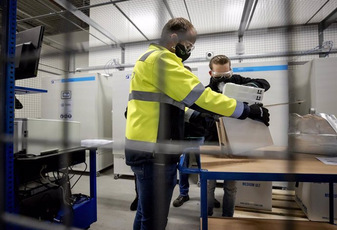26 December 2020, Netherlands, Oss: Employees unpack the first doses of Pfizer/BioNTech coronavirus vaccines to be stored in a freezer of the company Movianto in the industrial park Vorstengrafdonk. The vaccines come from the Pfizer factory in Puurs, a 