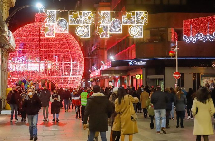 Transeúntes pasean bajo las luces navideñas, en Vigo, Galicia (España), a 25 de diciembre de 2020. Vigo está cerrada perimetralmente, pero abierta entre el 23 y 25 de diciembre para permitir encuentros familiares.