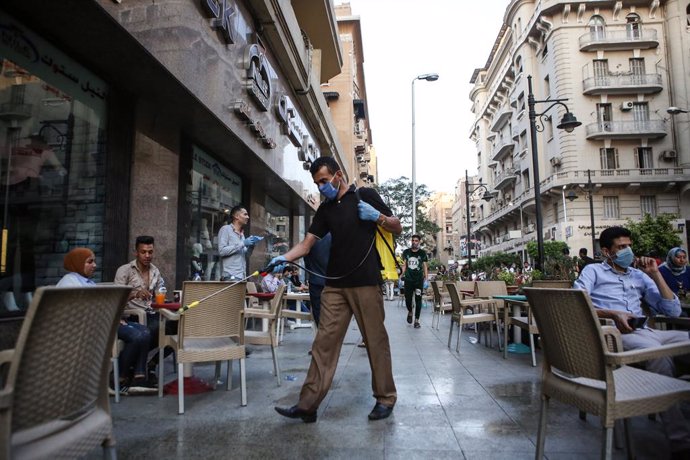 27 June 2016, Egypt, Cairo: A man sprays disinfectant outside a coffee following the easing of the Coronavirus (Covid-19) lockdown restrictions. Egyptian authorities allowed the partial reopening of businesses in an attempt to mitigate the economic impa