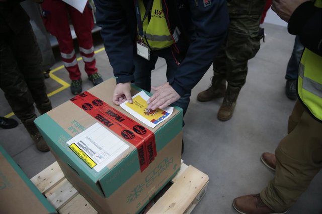 Personal de los laboratorios que han desarrollado las vacunas, Pfizer y BioNtech abren la caja con las dosis para entregarlas a técnicos de la Agencia Española de Medicamentos y Productos Sanitarios para su certificación y a personal del Ejército que reco