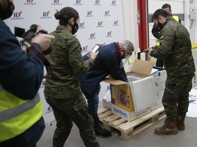 Personal de los laboratorios que han desarrollado las vacunas, Pfizer y BioNtech abren la caja con las dosis para entregarlas a técnicos de la Agencia Española de Medicamentos y Productos Sanitarios