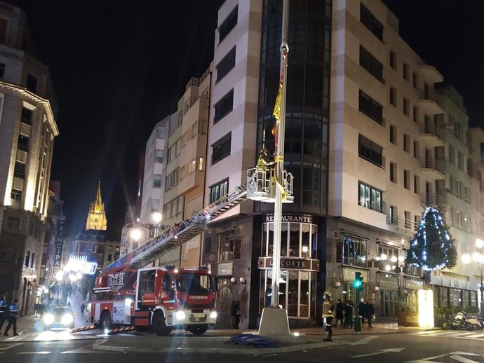 Bomberos sujetan la bandera de España con motivo de la llegada de la borrasca 'Bella'