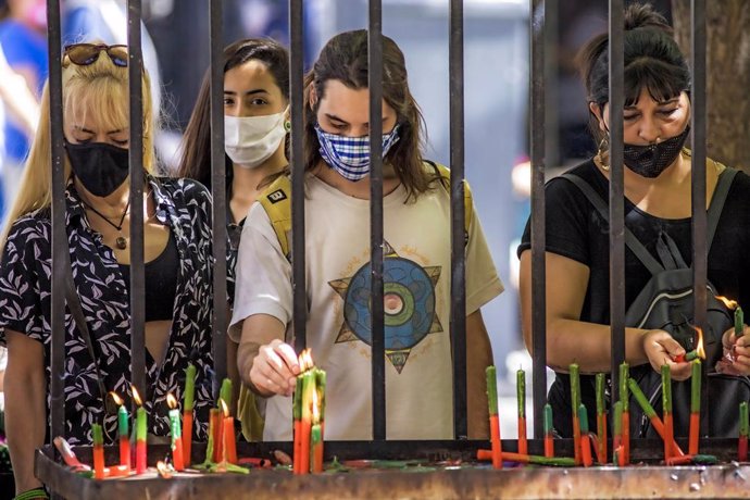 03 December 2020, Argentina, Buenos Aires: People wearing face masks light candles as they pray. Photo: Roberto Almeida Aveledo/ZUMA Wire/dpa