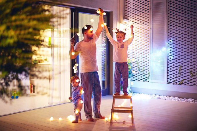 Padre con sus hijos colocando una guirnalda de luces navideñas-