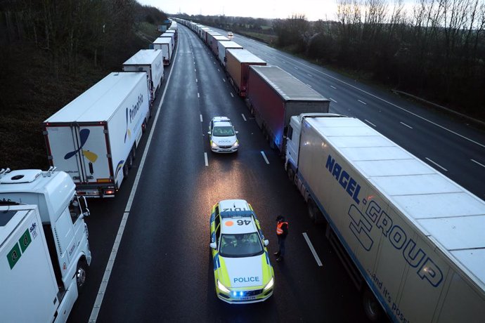 22 December 2020, England, Ashford: A lorry driver talks to police officers as they patrol along the M20 in Kent where lorries are parked after the Port of Dover was closed and access to the Eurotunnel terminal was suspended following the French governm