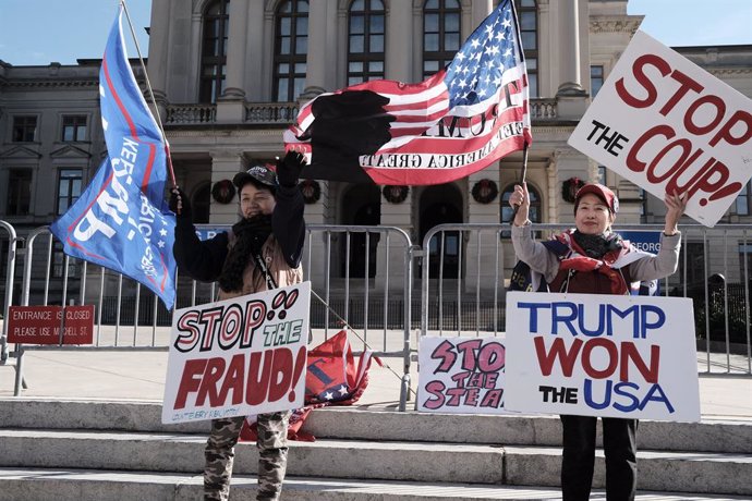19 December 2020, US, Atlanta: Two demonstrators hold placards on the steps of the Georgia Capitol building in Atlanta during a rally to support US President Donald Trump. Photo: John Arthur Brown/ZUMA Wire/dpa