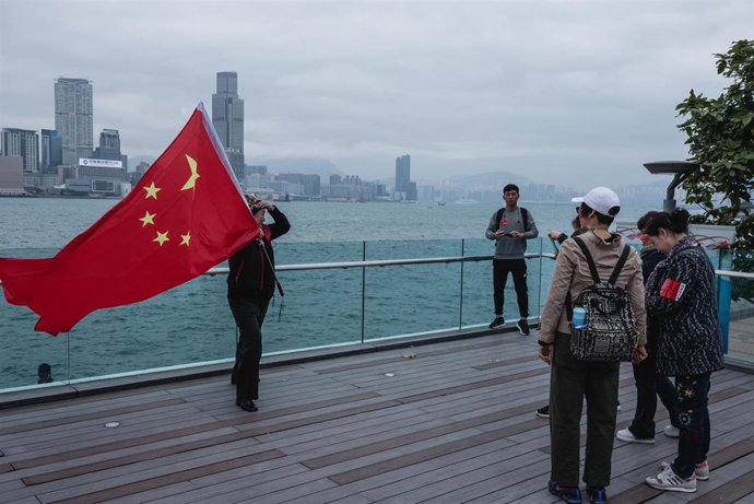 15 December 2019, China, Hong Kong: A pro-government protester poses for a photo while holding a Chinese flag during a rally. Thousands of pro-government protesters gathered in support of the Hong Kong police in their handling of the protests that have 