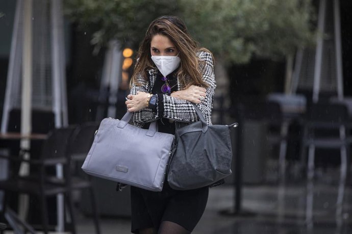 Una mujer camina bajo la lluvia sin paraguas. En Sevilla (Andalucía, España), a 04 de diciembre de 2020.