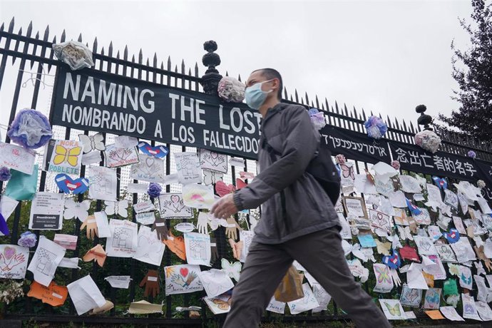 Un hombre con mascarilla junto a un memorial en recuerdo a los fallecidos por coronavirus en EEUU