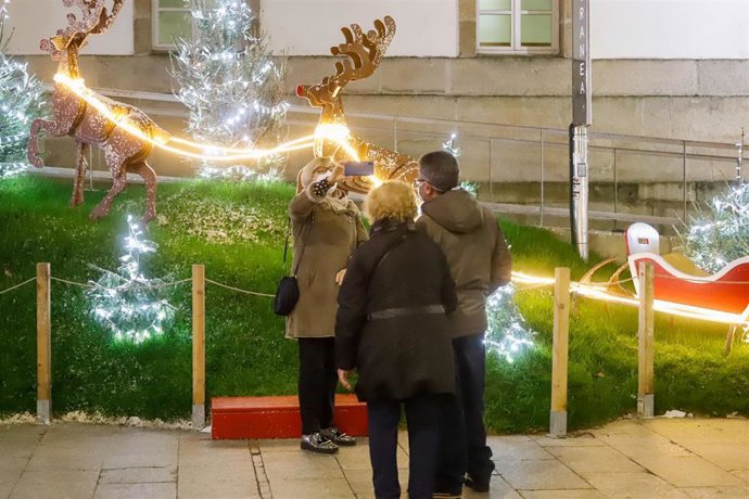 Transeúntes se hacen fotos bajo las luces navideñas, en Vigo, Galicia (España), a 25 de diciembre de 2020. Vigo está cerrada perimetralmente, pero abierta entre el 23 y 25 de diciembre para permitir encuentros familiares.
