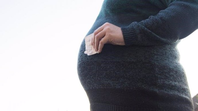 Mujer embarazada en la foto sosteniendo un paquete de pastillas.