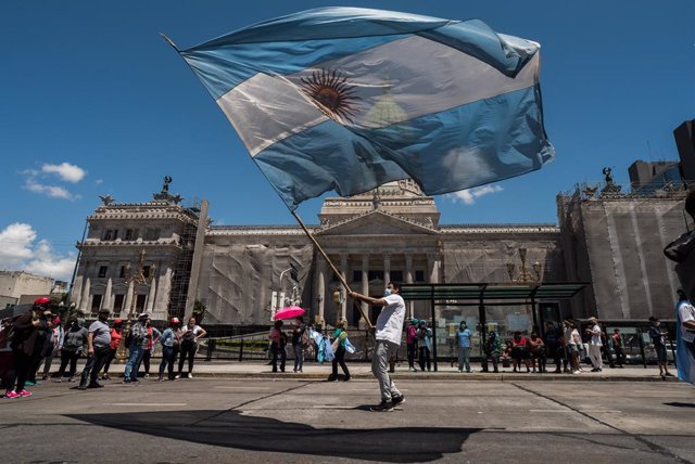 Un hombre hondeando la bandera de Argentina en la Plaza de Mayo