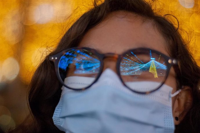 Una mujer en Colombia viendo las luces de Navidad con mascarilla en plena pandemia del coronavirus.