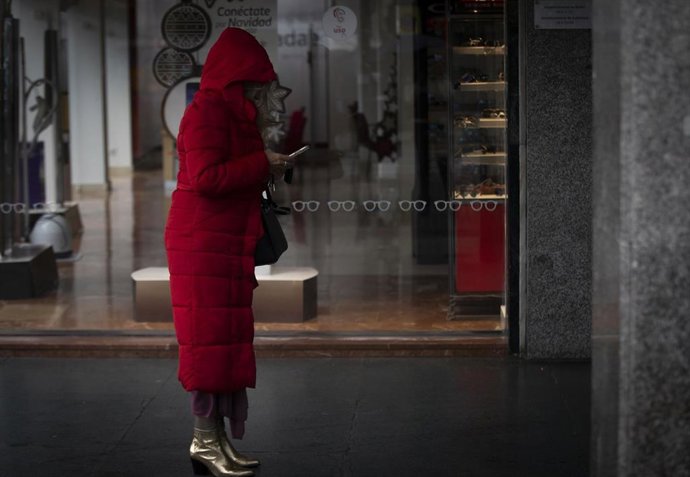 Una mujer bajo un soportal espera que cese la lluvia. En Sevilla (Andalucía, España), a 04 de diciembre de 2020.