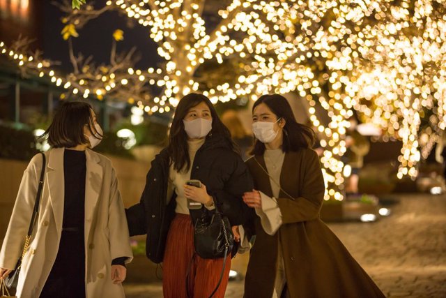 11 December 2020, Japan, Tokyo: Women wearing face masks walk down a passage with Christmas decoration in Ebisu. Photo: Stanislav Kogiku/SOPA Images via ZUMA Wire/dpa